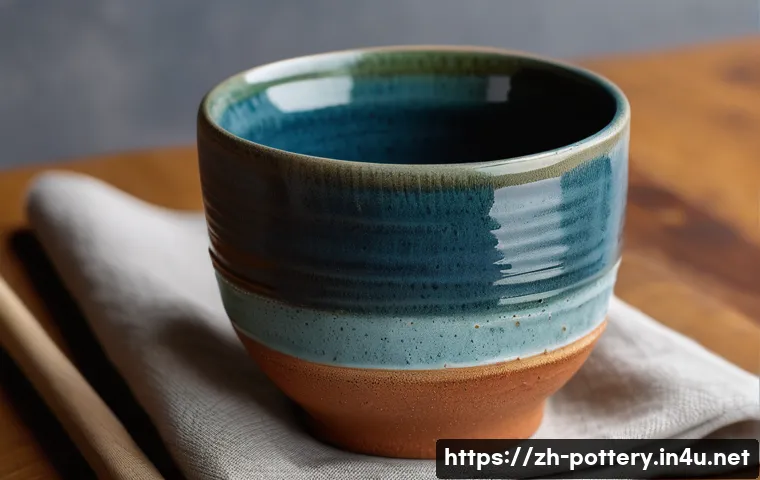 핸드빌딩 기법 - A close-up of a handcrafted ceramic cup showcasing natural finger indentations and subtle texture va...